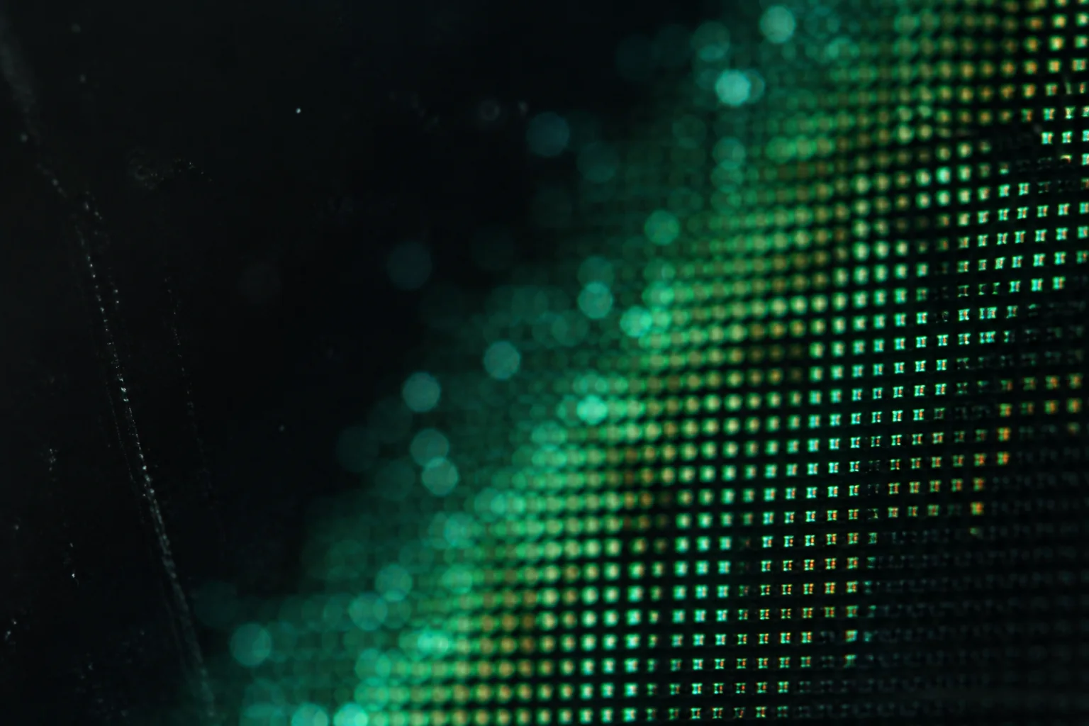 Macro view of green display pixels emerging from darkness